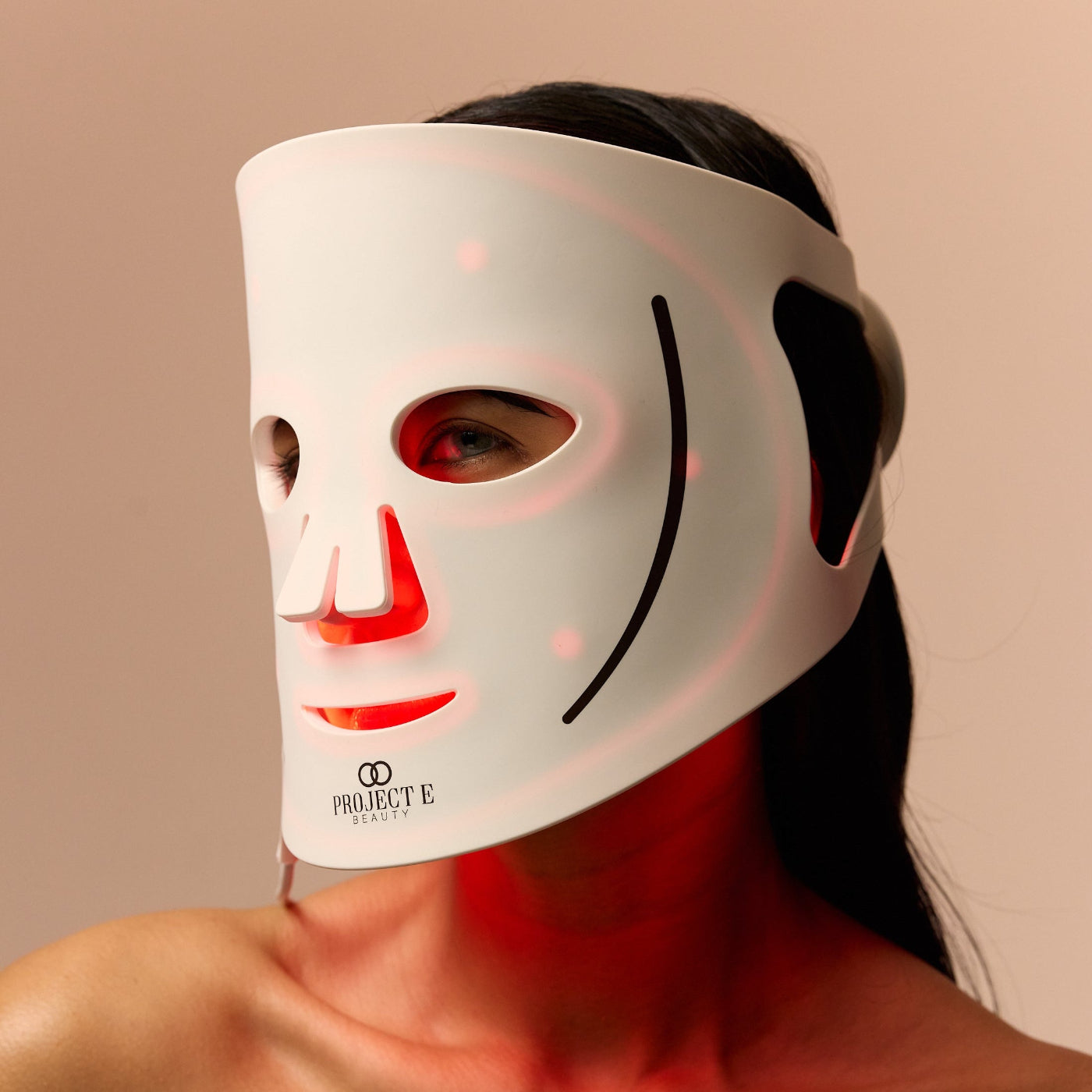 Model wearing red light LED mask for glowing skin.